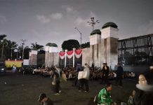 Fakta Demo DPR 27 Agustus: Kenapa Ojol & Warga Bertahan? Ilustrasi massa sipil dan driver ojol dengan jaket hijau bertahan di jalanan saat malam hari dalam aksi Demo DPR 27 Agustus.